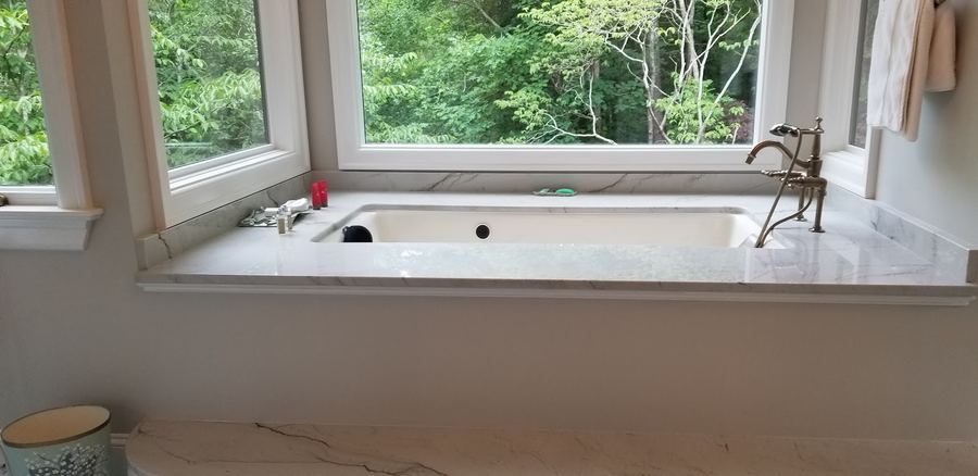Soaking tub with marble surround under a picture window